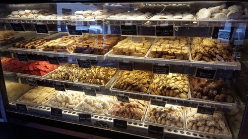 A display case filled with various colorful pastries and sweets, labeled with names of each treat.