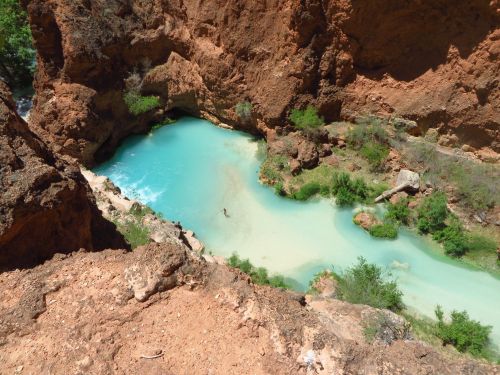 Aerial view of a turquoise river winding through rocky cliffs and lush greenery.