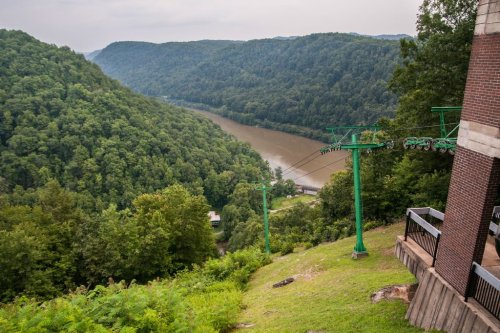 A scenic view of a river winding through lush green hills, with a cable car structure in the foreground.