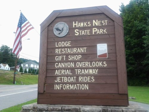 Sign for Hawks Nest State Park listing amenities: lodge, restaurant, gift shop, canyon overlooks, aerial tramway, jetboat rides.