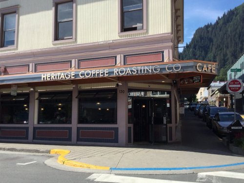 Exterior of Heritage Coffee Roasting Co. Café, featuring a sign and a view of a street in a mountainous area.