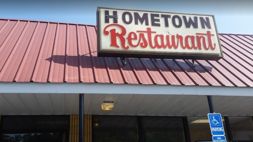 Sign for "Hometown Restaurant" on a building with a red metal roof and accessible parking sign.