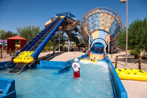 A water park featuring a large slide and a funnel ride, with lifeguards and guests enjoying the attractions.