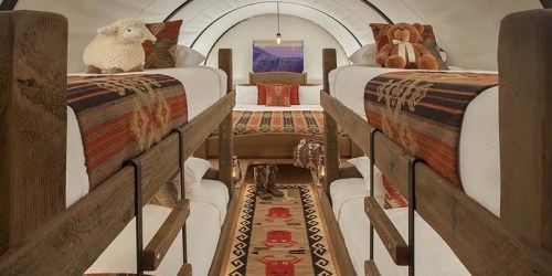 Cozy interior of a cabin with bunk beds, plush toys, and warm decor, featuring a patterned rug and soft lighting.