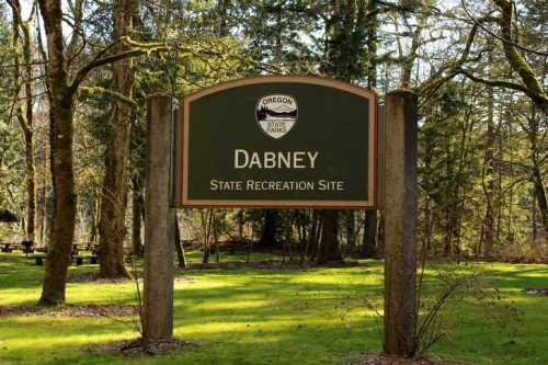Sign for Dabney State Recreation Site in Oregon, surrounded by trees and grassy area.