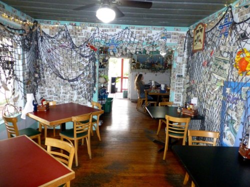 Interior of a restaurant with dollar bills on the walls, wooden tables, and a cozy, nautical-themed decor.