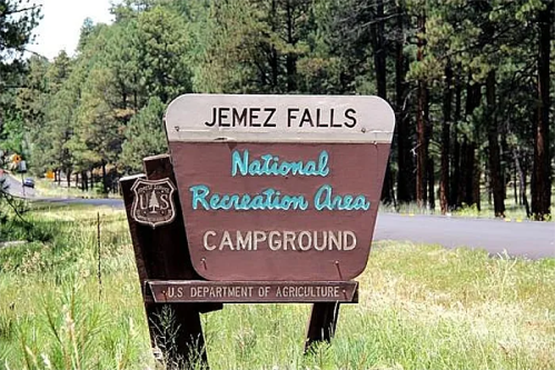 Sign for Jemez Falls National Recreation Area Campground, surrounded by trees and grass.