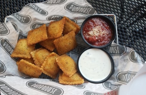 A plate of golden-brown fried ravioli served with marinara and ranch dipping sauces.