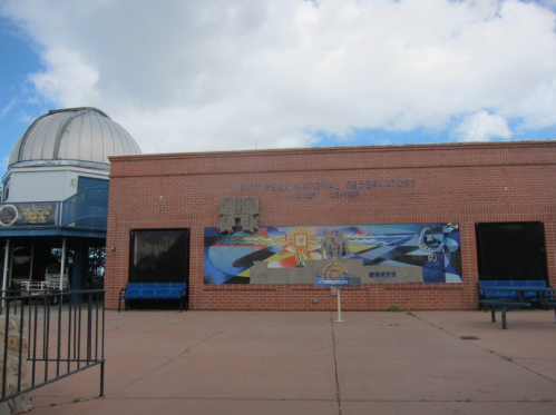 Exterior of the Kitt Peak National Observatory visitor center, featuring a mural and a domed observatory structure.