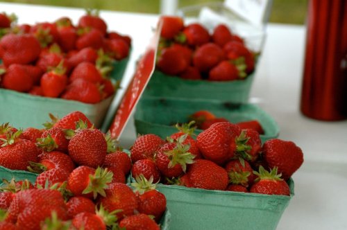 Baskets of fresh, ripe strawberries on a table, showcasing their vibrant red color and green tops.