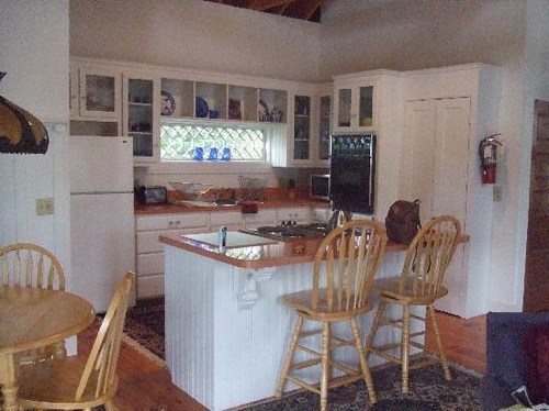 A cozy kitchen with white cabinets, a wooden island, and a dining table, featuring a warm, inviting atmosphere.