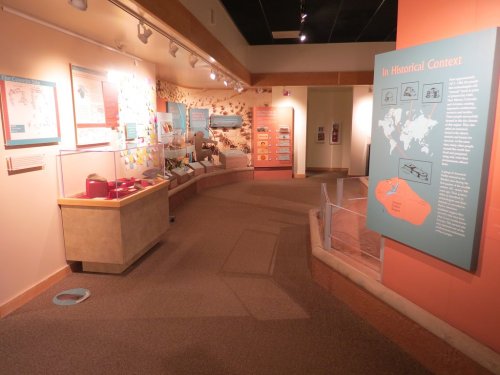 A museum exhibit featuring informational panels, displays, and a curved pathway in a well-lit space.