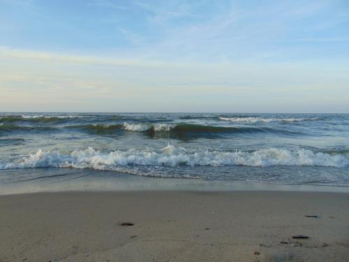 Waves gently rolling onto a sandy beach under a clear blue sky.