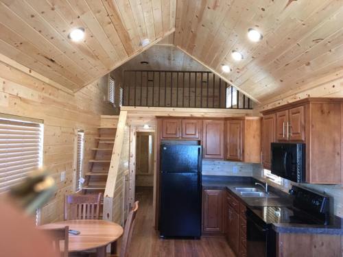 Cozy wooden interior of a small cabin with a kitchen, dining area, and a loft accessible by stairs.