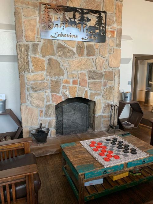 Cozy lodge interior featuring a stone fireplace, wooden furniture, and a checkers game on a rustic table.
