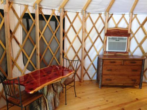 Interior of a yurt featuring a wooden table, chairs, dresser, and an air conditioning unit on the wall.