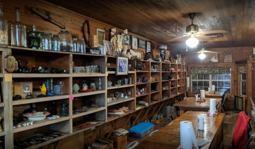 A rustic interior of a shop with wooden shelves filled with various vintage items and memorabilia.