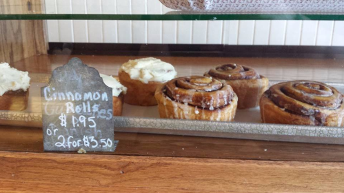 A display case with cinnamon rolls and a sign listing prices: $1.95 each or 2 for $3.50.