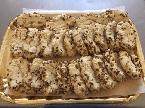 A tray of freshly baked cookies with a crumbly texture and chopped nuts on the edges, arranged neatly.