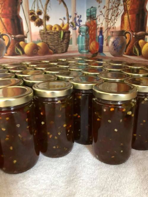 A row of jars filled with a dark, chunky substance, set against a colorful, still-life background.