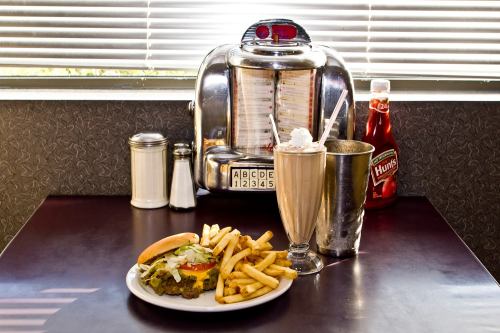 A classic diner scene featuring a burger with fries, a milkshake, and a retro jukebox in the background.