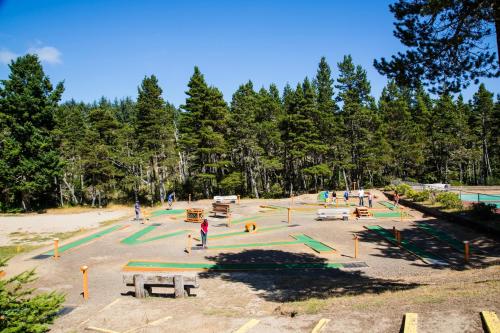 A mini-golf course surrounded by trees, with people playing and enjoying the sunny day.