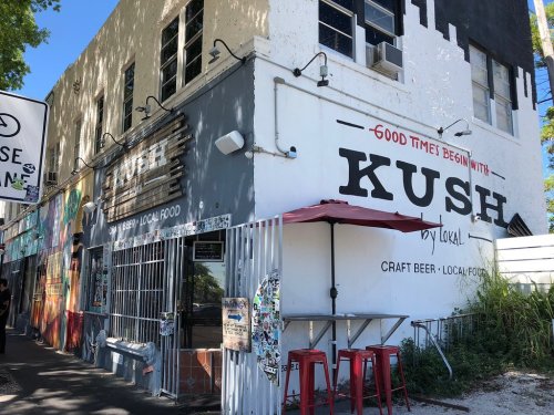 Exterior of Kush, a vibrant restaurant with colorful murals, offering craft beer and local food.