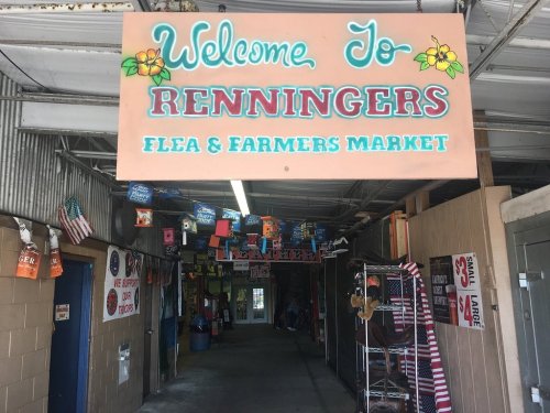 Sign welcoming visitors to Renningers Flea and Farmers Market, with colorful banners and flags hanging in the entrance.