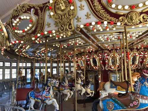 A beautifully decorated carousel with ornate details and colorful horses, illuminated by bright lights.
