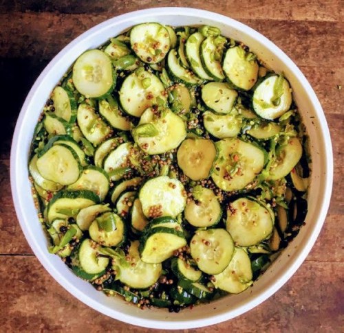A large bowl filled with sliced cucumbers mixed with spices and herbs.