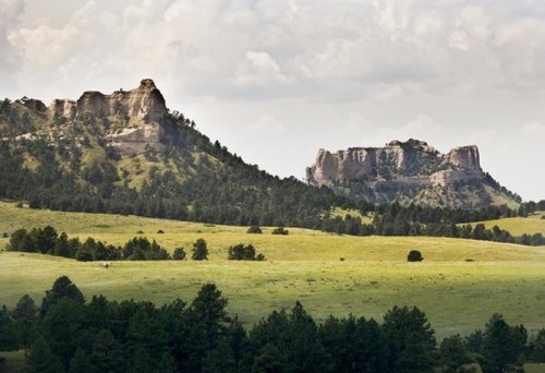 A scenic view of rolling green hills with rocky outcrops under a cloudy sky.