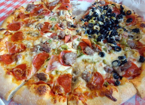 A large pizza divided into two halves: one with pepperoni and the other topped with olives, green peppers, and sausage.