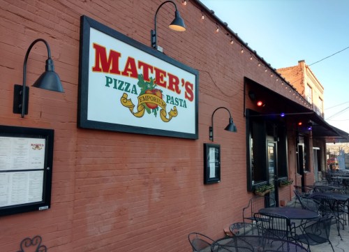 Exterior of Mater's Pizza Emporium, featuring a colorful sign and outdoor seating with tables and chairs.