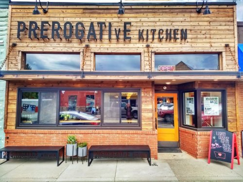 Exterior of Prerogative Kitchen, featuring wooden paneling, an open sign, and a chalkboard menu outside.