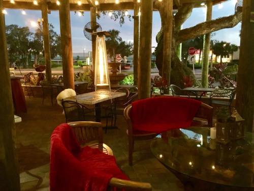 Cozy outdoor seating area with red blankets, a glass table, and warm lighting under a wooden structure.