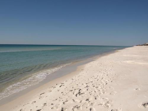 A serene beach with soft white sand and calm turquoise waters under a clear blue sky.