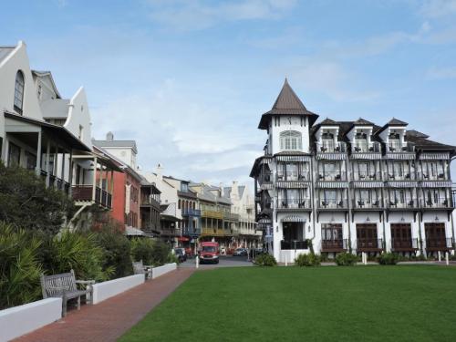 Charming street view with colorful buildings, a grassy area, and a vintage fire truck in a coastal town.