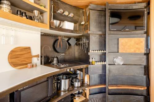 A modern kitchen with curved shelves, a stove, microwave, and various cooking utensils neatly organized.