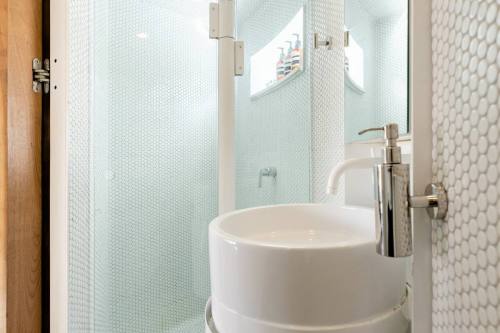 Modern bathroom featuring a glass shower, white sink, and hexagonal tile walls.