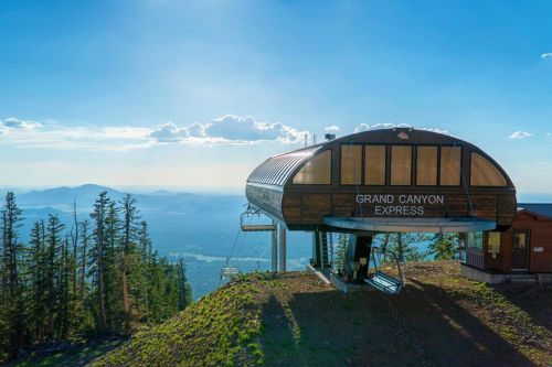 A modern ski lift station named "Grand Canyon Express" set against a scenic mountain backdrop and clear blue sky.