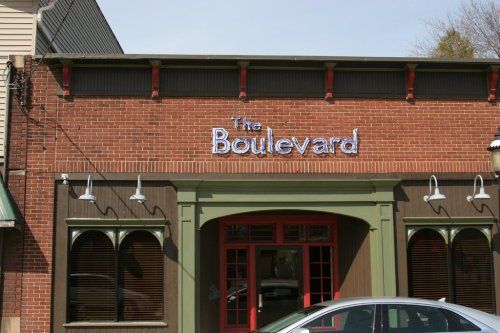 A brick building with a sign reading "The Boulevard" above a red door and arched windows.
