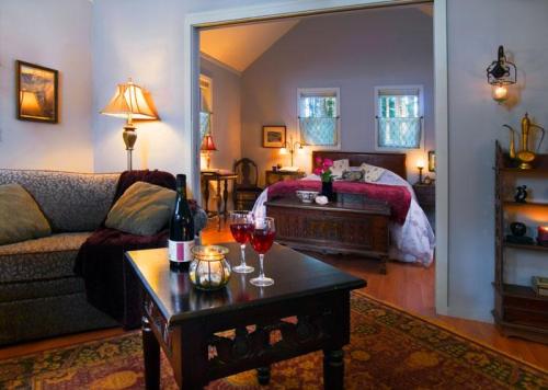 Cozy living space with a sofa, wine, and candles, leading to a warmly lit bedroom with a bed and decorative accents.