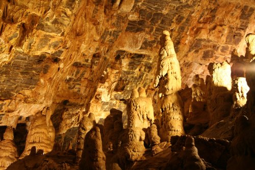 Stalactites and stalagmites in a dimly lit cave, showcasing intricate rock formations and textures.