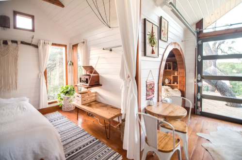 Cozy interior of a tiny house featuring wooden furniture, large windows, and a warm, inviting atmosphere.