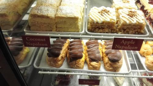 Display case with pastries: Coconut Napoleon, Apple Napoleon, and Éclairs, all beautifully arranged.