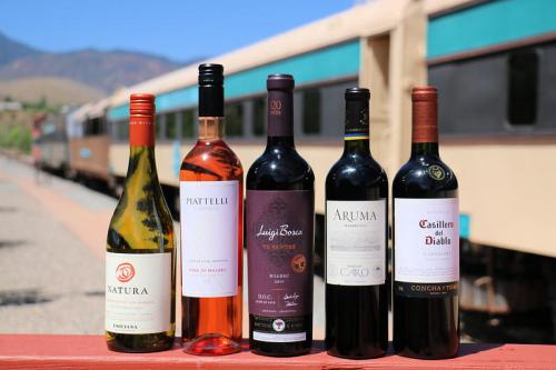 Five bottles of wine in a row: white, rosé, and red varieties, with a train in the background.