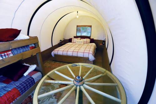 Cozy interior of a glamping tent featuring a double bed, bunk beds, and rustic decor.
