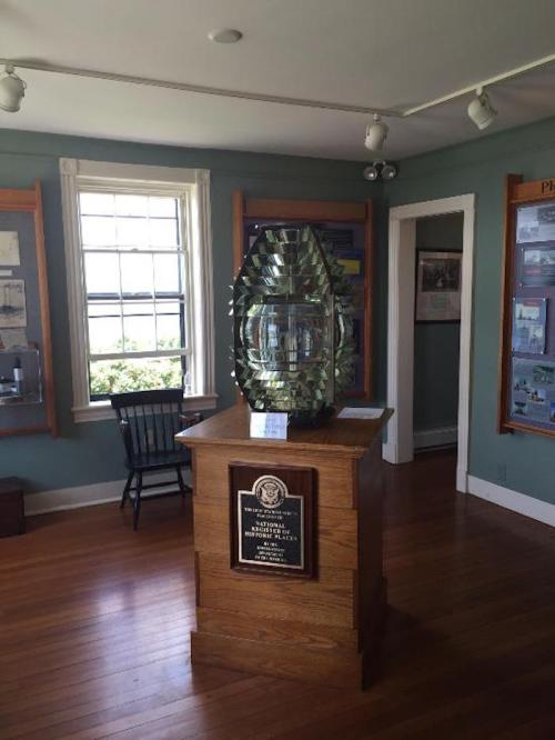 A glass trophy displayed on a wooden pedestal in a museum room with informational panels and a window.