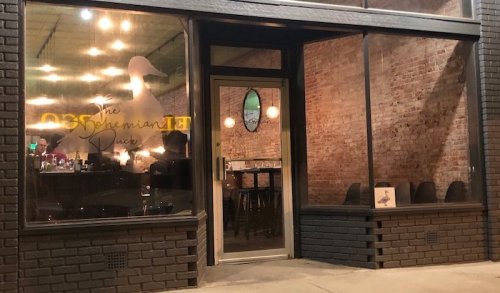 Exterior view of a restaurant called "The Speckled Duck," featuring a glass door and brick walls.