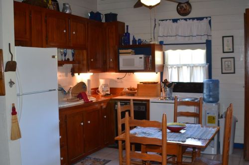 Cozy kitchen with wooden cabinets, a white refrigerator, and a dining table set for a meal. Bright and inviting atmosphere.